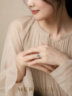MERVAUX blue oval three-stone diamond ring worn, hands folded